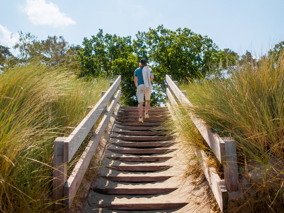 ©FilmVision Rückansicht einer Person, die eine Treppe am Strand hochsteigt